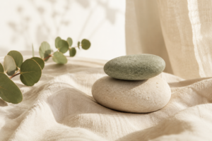 Two smooth stones balanced on linen beside eucalyptus in warm light