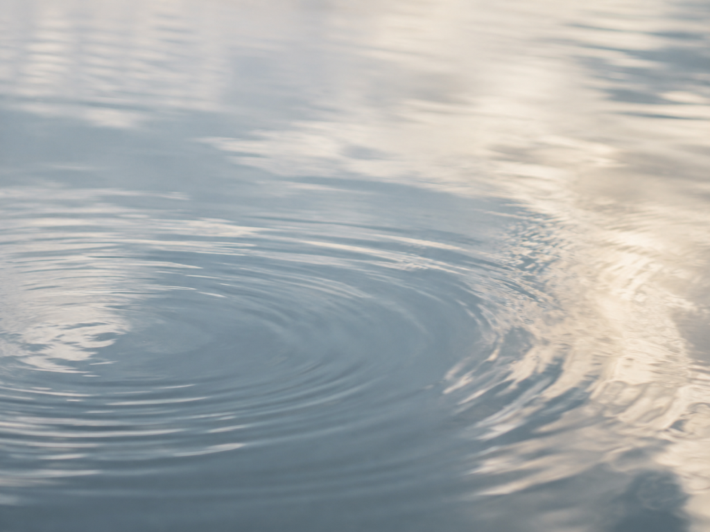 Gentle ripples spreading across still water in soft light