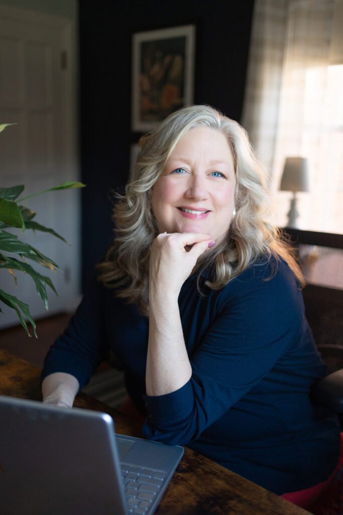 Kate Bergman, NARM®-certified therapist, seated with hand at chin in a navy blouse